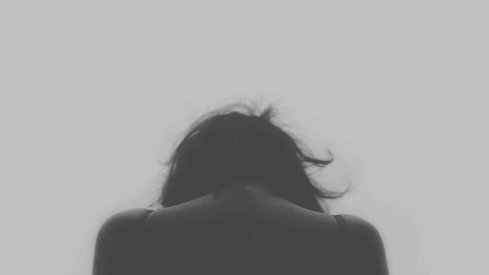 From the back, a woman bowing her head in sadness