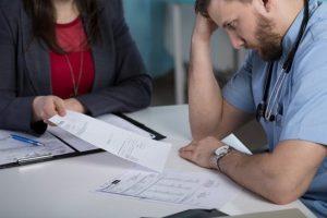 doctor in distress while reviewing paperwork