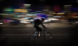 A cyclist riding his bike through a city street at night