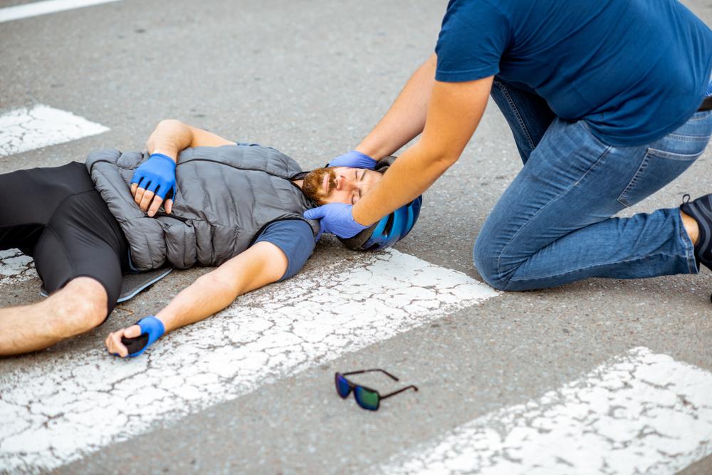 man lying in crosswalk while another man helps him