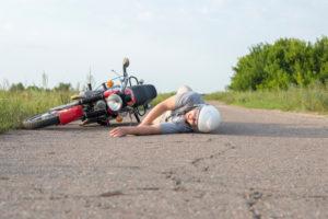 a man lying on the asphalt near his motorcycle