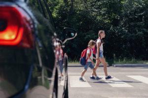 car waits while school children cross street