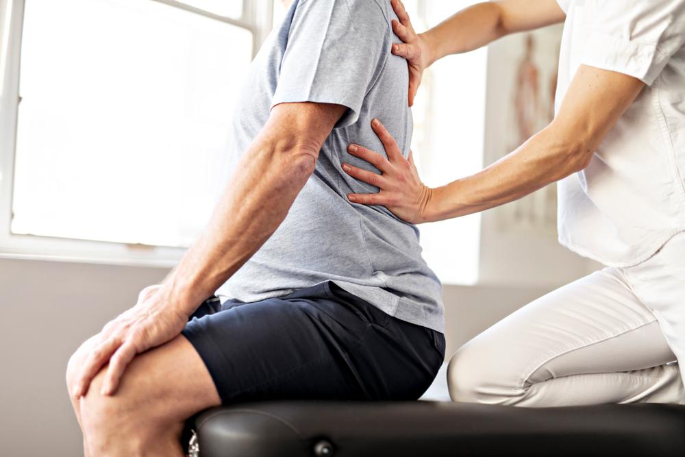 physical therapy worker helping a patient with back pain
