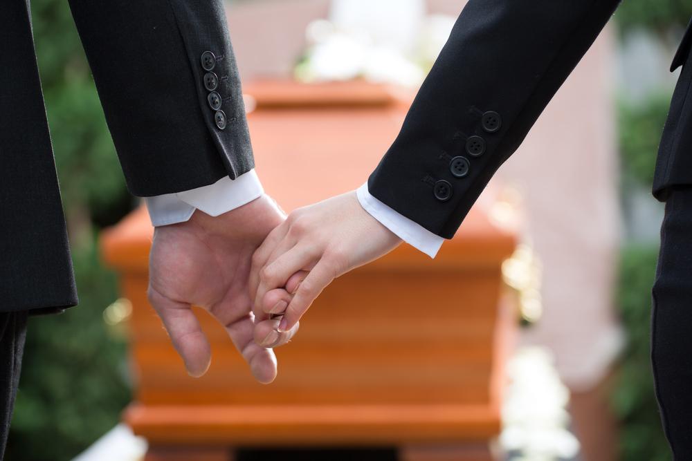 family members holding hands at a funeral