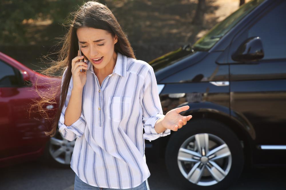stressed woman calls insurance after car accident