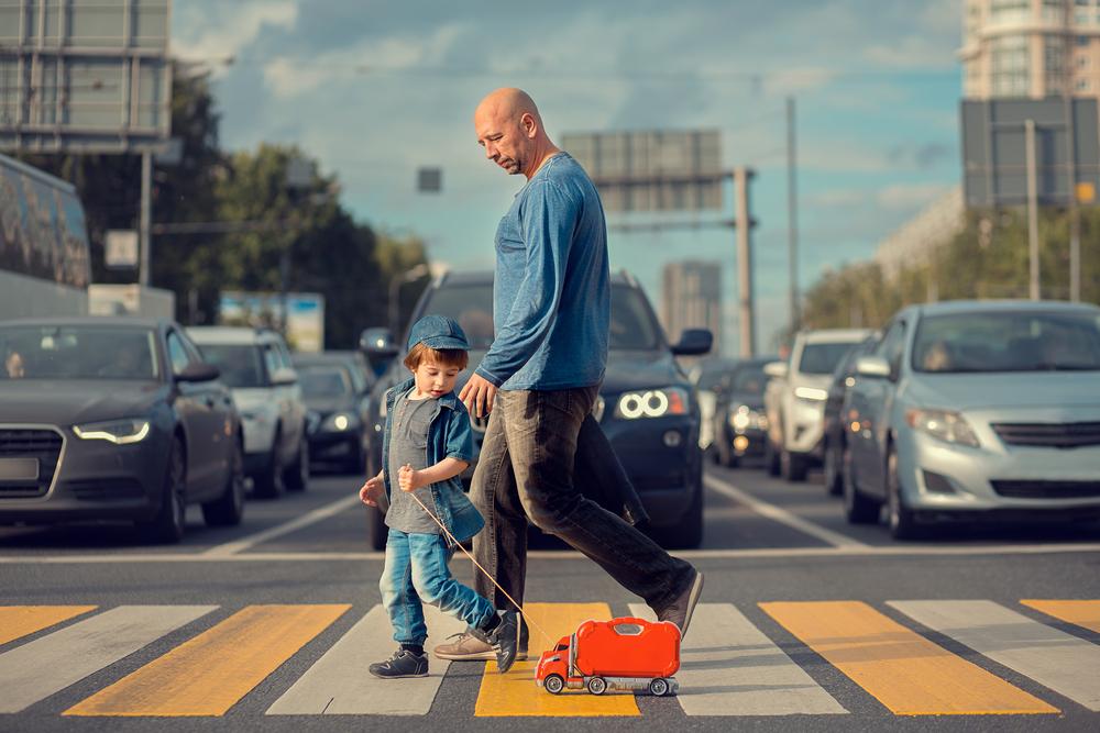 traffic waits while boy and his dad cross the stree
