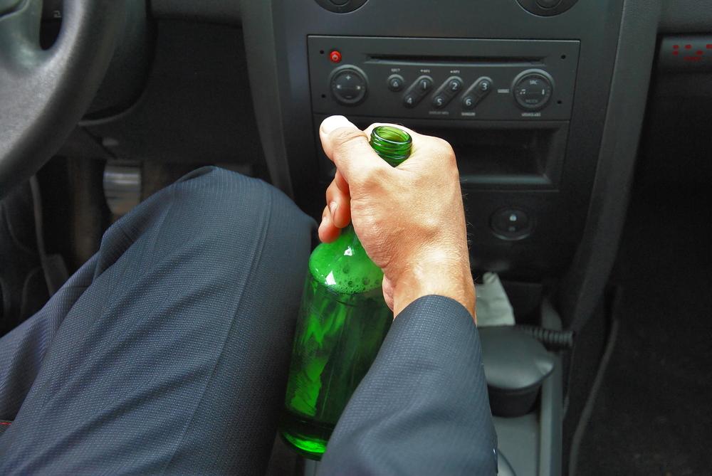 driver holds an open bottle of alcohol
