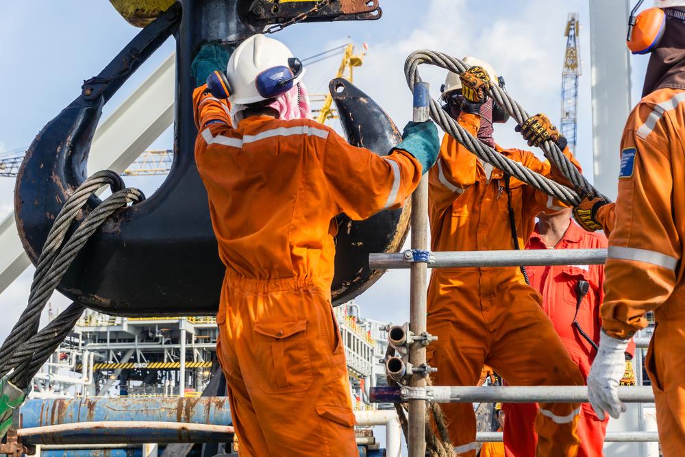 offshore workers install sling onto crane block