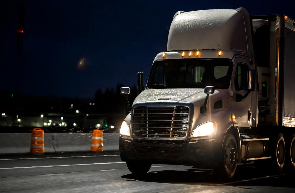 semi-truck transports cargo on rainy night