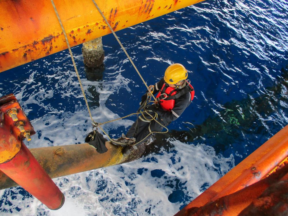 abseiler inspects pipe on offshore drill