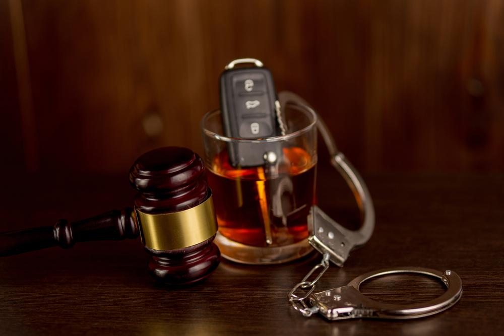 car key and handcuffs in whiskey glass next to gavel