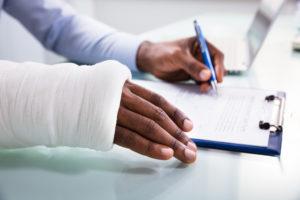 injured worker with bandaged hand fills out insurance claim