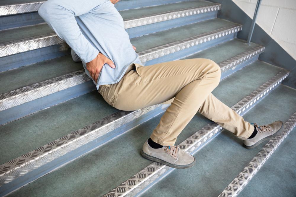 man experiencing back pain from slip and fall on stairs
