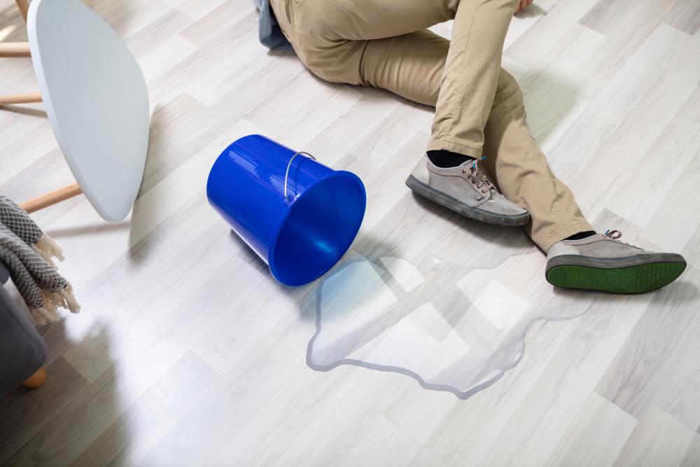 man slips and falls on wet floor from spilled bucket