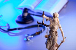 scales of justice with stethoscope and gavel in background