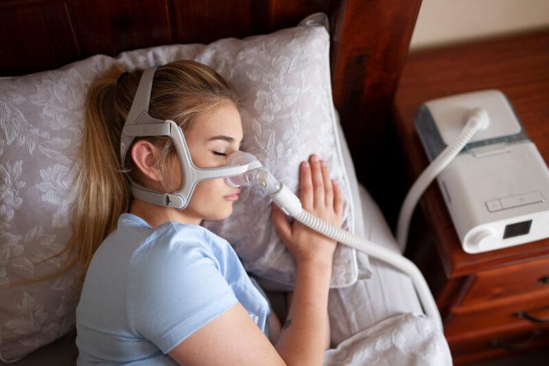 Woman lying in bed with CPAP attached to nose