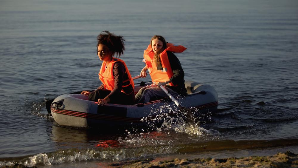 two women wearing life vests in raft seeking help after boating wreck
