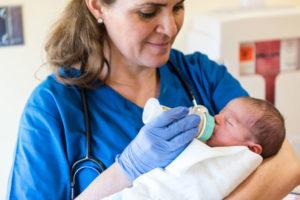 Female medical worker bottle feeding small baby