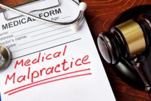 gavel stethoscope and clipboard reading malpractice