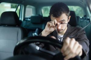 a male driver rubbing his eyes tiredly