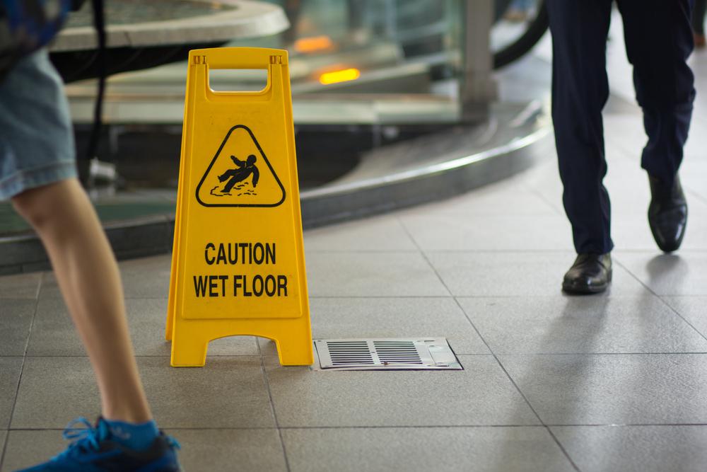 people walking past a wet floor sign