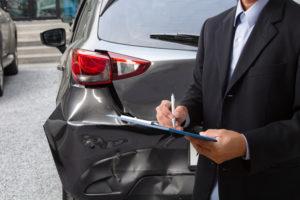insurance agent marking up car damage