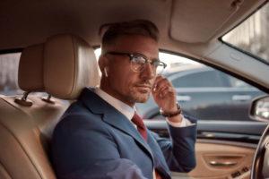 businessman adjusting headphones while driving